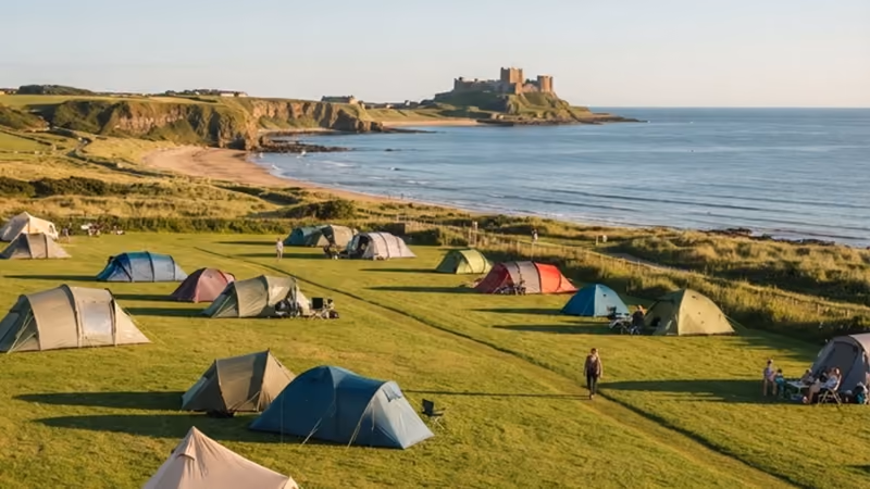Tents pitched across the grass field above the bay, the castle beyond