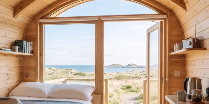 The inside of a pod in morning light, bed made up under the arched window