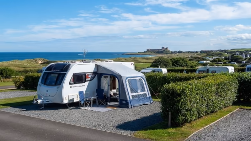 A caravan with its awning out on a hardstanding pitch above the sea